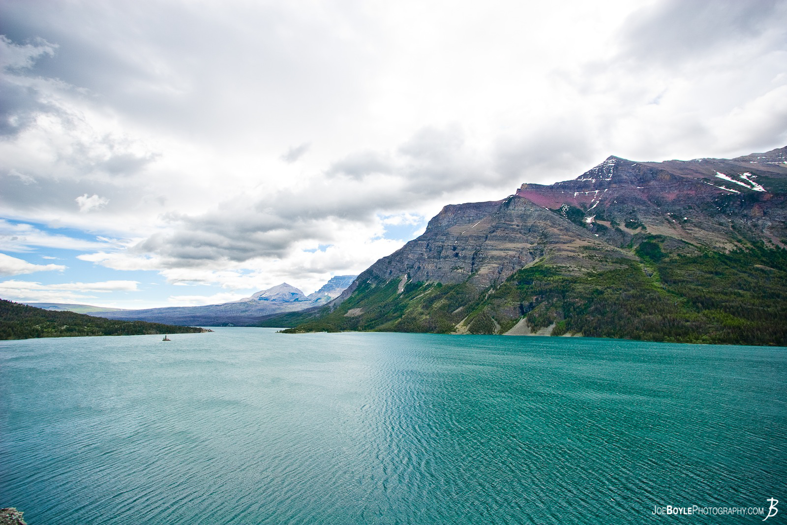  This is one of the first images that I captured on my trip to Glacier National Park (GNP). Beautiful green water, which is a Moraine Lake, with the mountain and clouds as a backdrop provided a very surreal experience!  