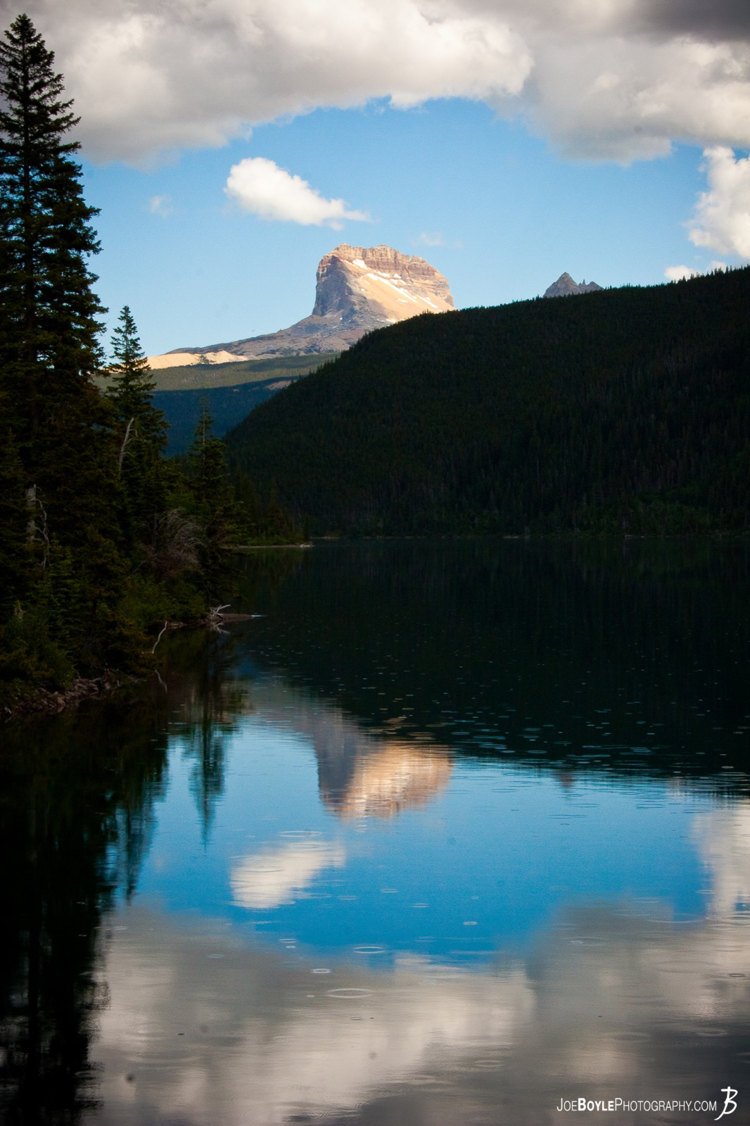  It was just beginning to rain but I was able to capture this image with the mountain being reflected in the nearby lake. I was surprised the sky has so much blue in it despite the rain. It actually worked out very nice as the clouds actually frame the mountain into the picture. 